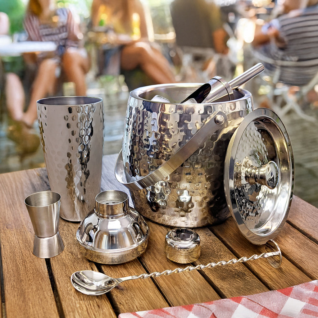 Cocktail bartending set with an ice bucket, shaker, mixing spoon, scoop, and jigger.  It's made of stainless steel and very shiny reflective finish.