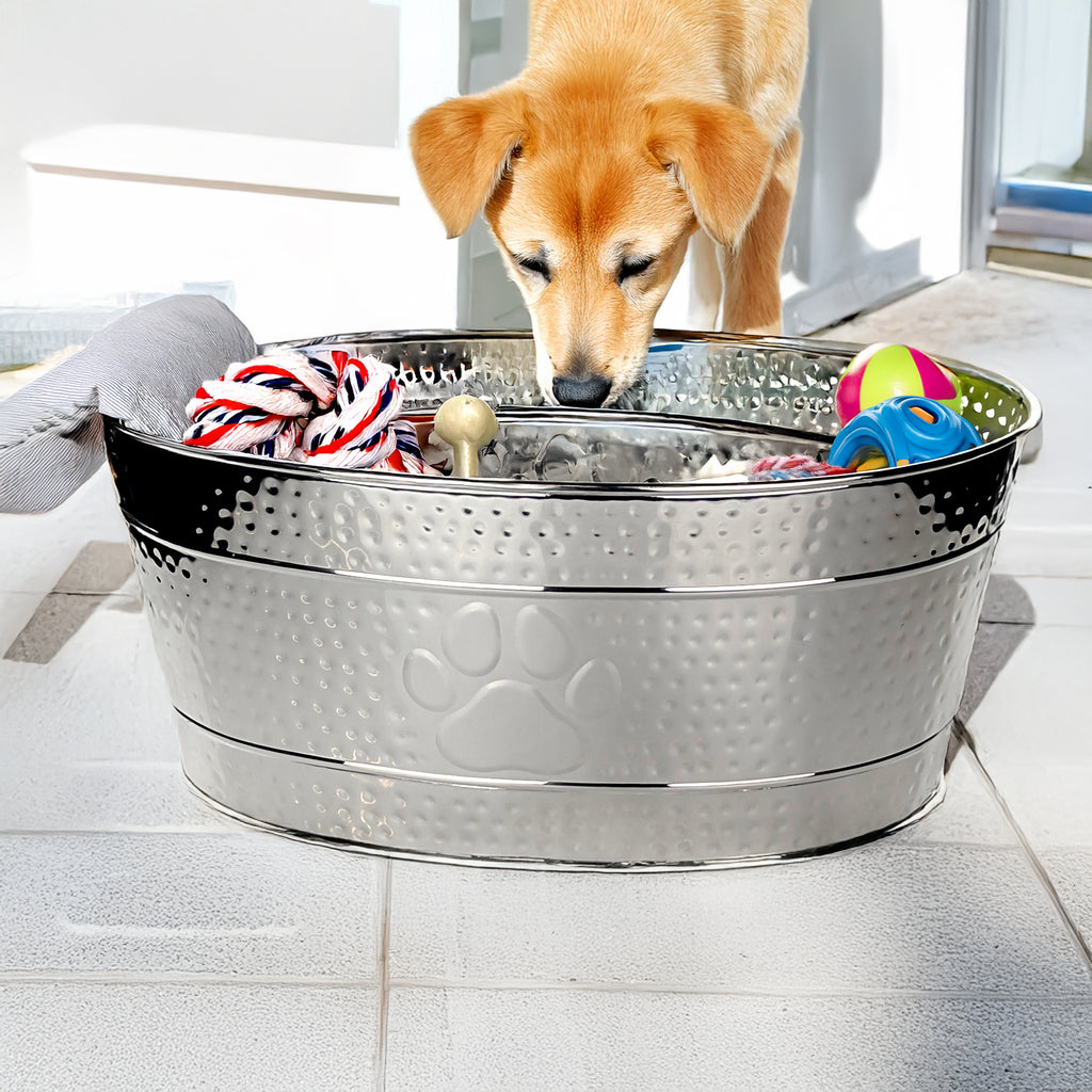 Large stainless steel dog toy storage bin with paw print filled with colorful dog toys in home setting