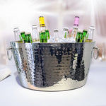 Stainless steel ice bucket that is very reflective and includes a hammered exterior.  The bucket includes to handles with bottles chilled by ice inside.