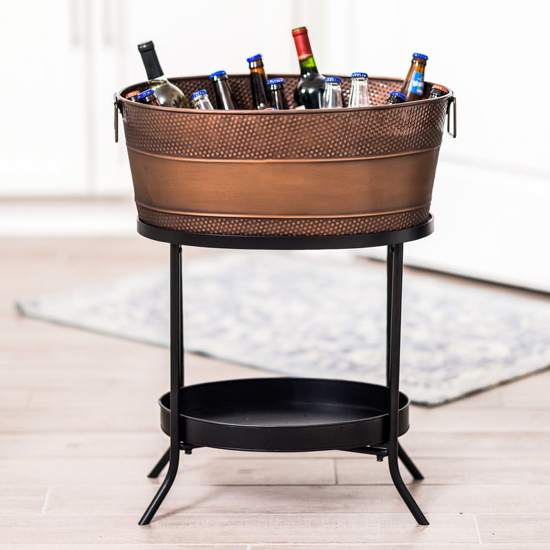 Large copper party tub with stand to chill beer, wine, and drinks at a party.  Stand is made of iron in matte black color and includes a bottom shelf or try to hold bottles of wine or other cocktail party accessories. 